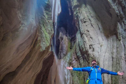 Escursionista nella gola di Lu Cugnuntu, illuminata da un raggio di luce tra pareti rocciose e muschio, lungo il trekking selvaggio in Valnerina.