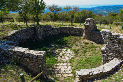 Resti di una neviera in pietra sul Monte Tezio, immersa nel paesaggio boscoso umbro con vista sul Lago Trasimeno.